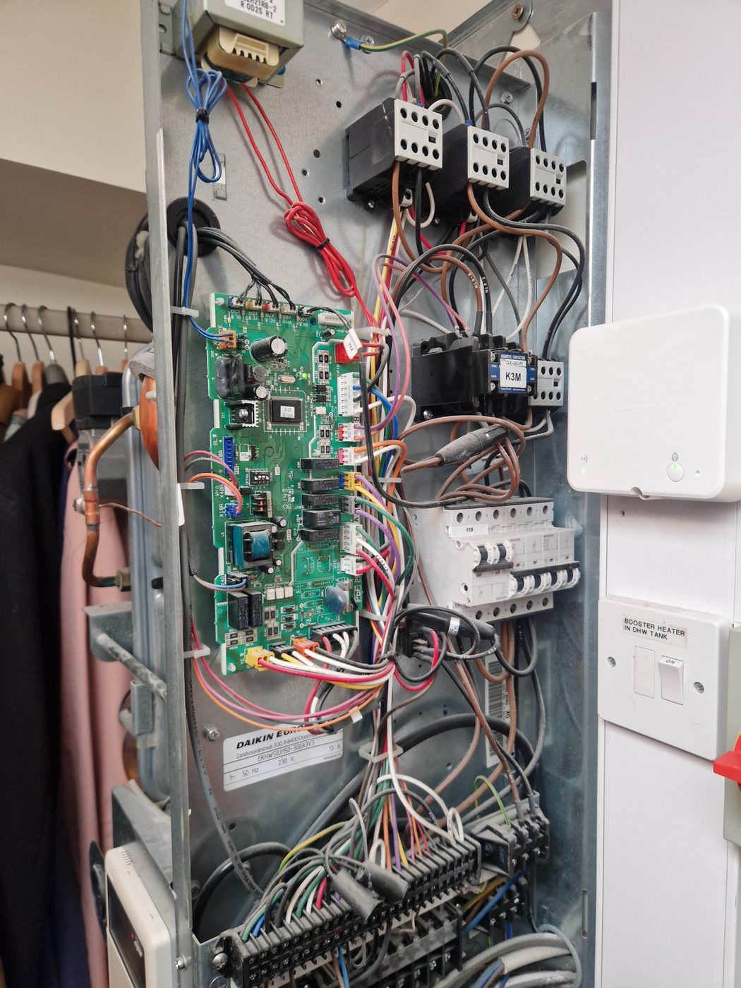 A heat pump control panel opened up showing the circuit board, wiring and breakers