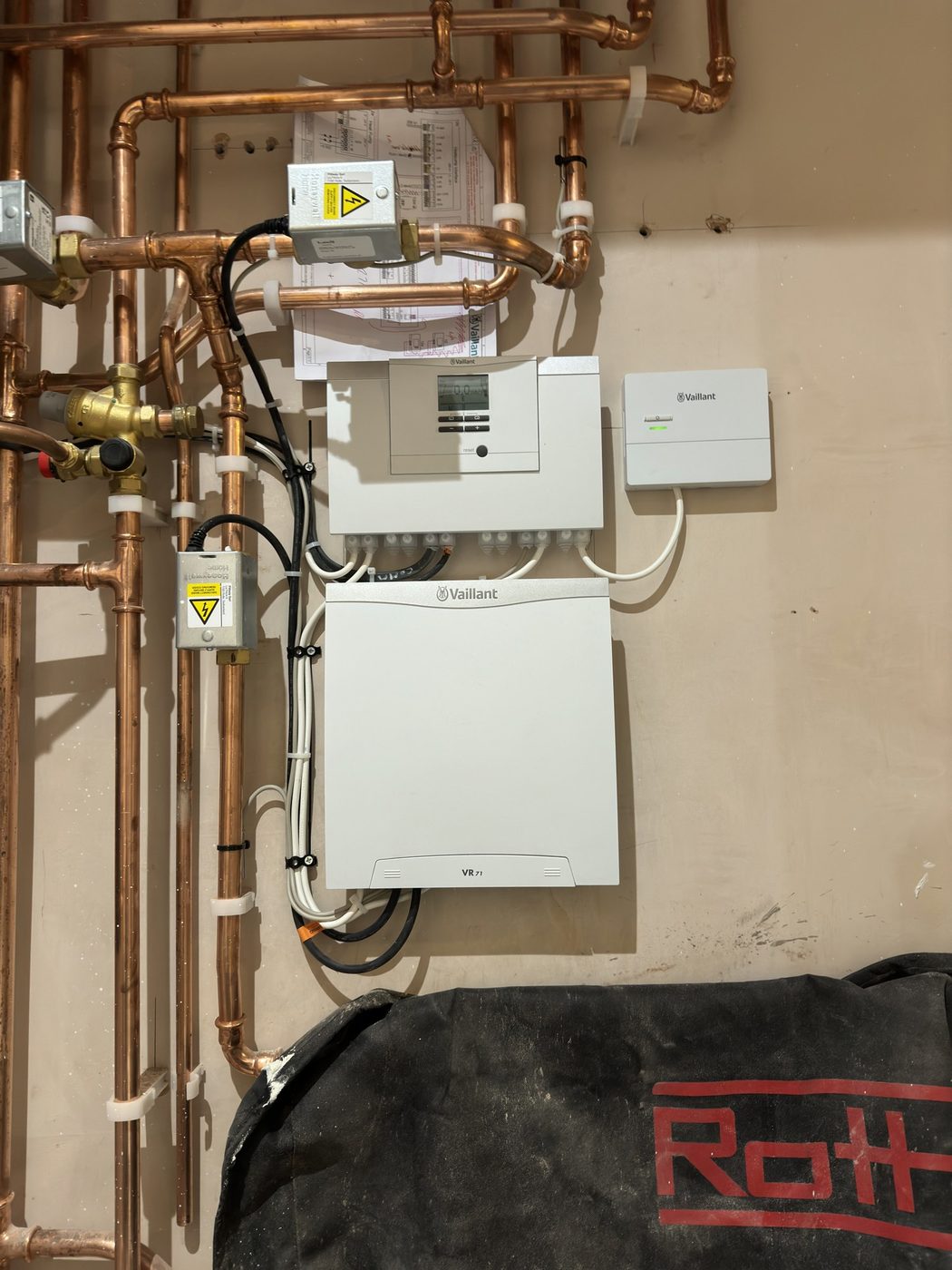 A Vaillant control unit and wiring centre with copper pipework behind a heat pump system