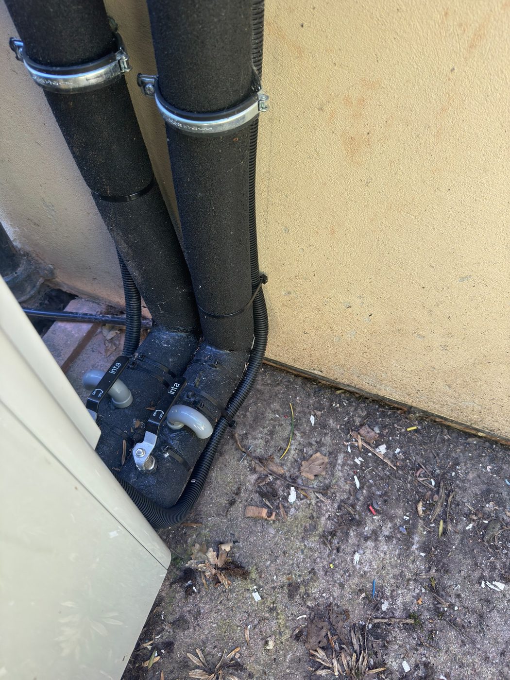 Insulated flow and return isolation valves at the base of an outdoor heat pump unit