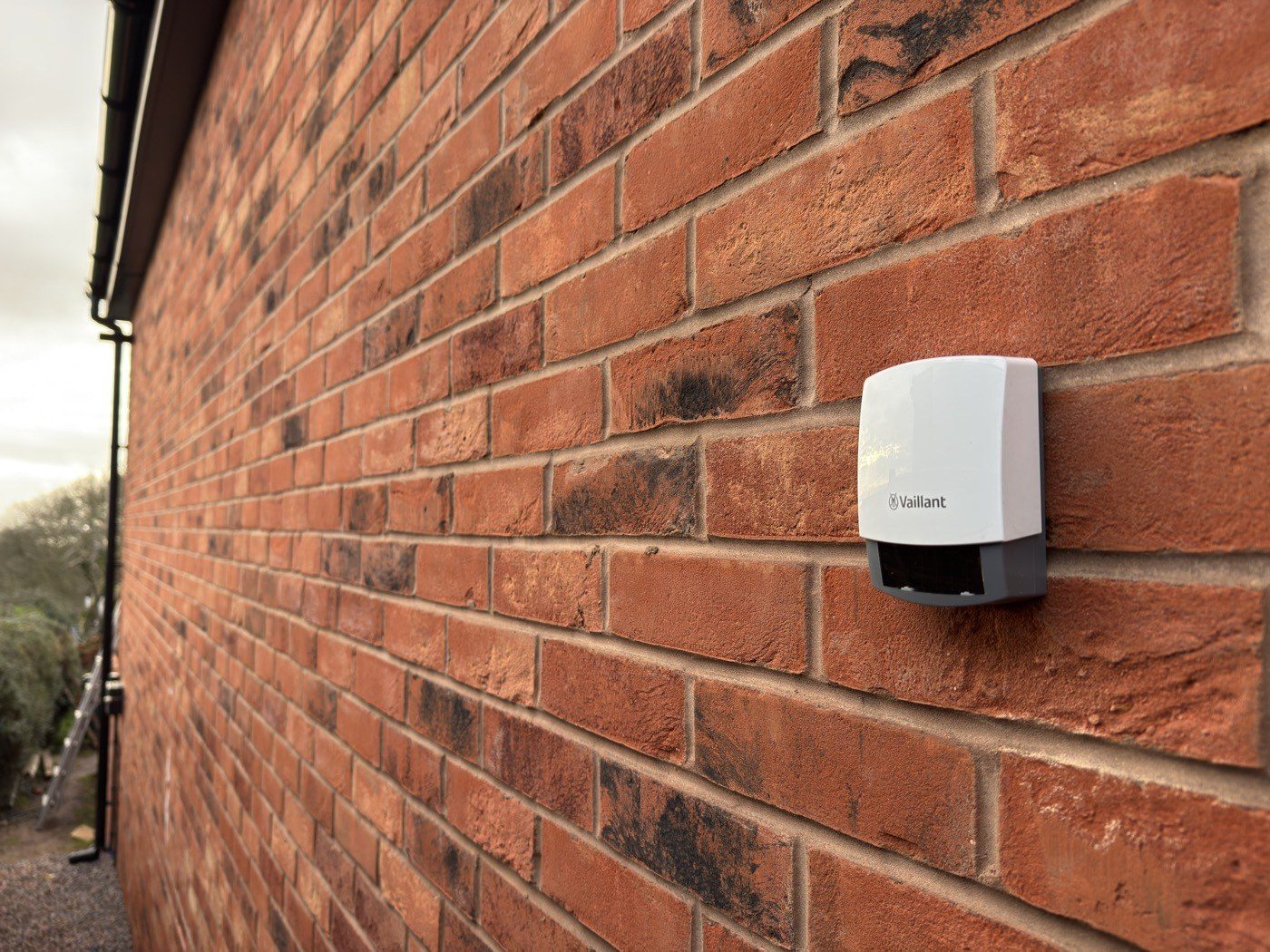 A Vaillant outdoor weather sensor mounted on a red brick wall