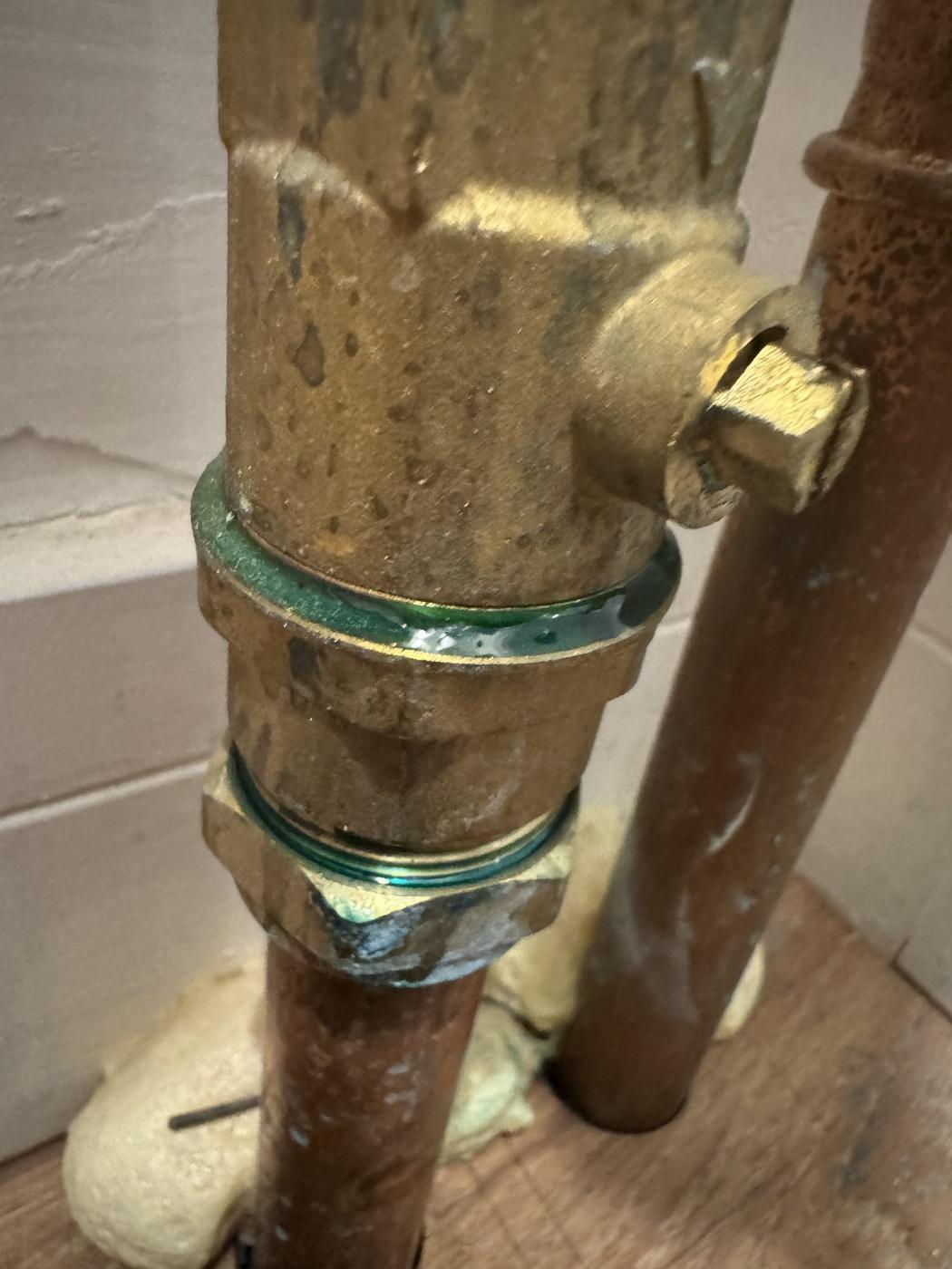 Leaking brass pipe joint with corrosion staining around the fitting, found on a system installed by another company