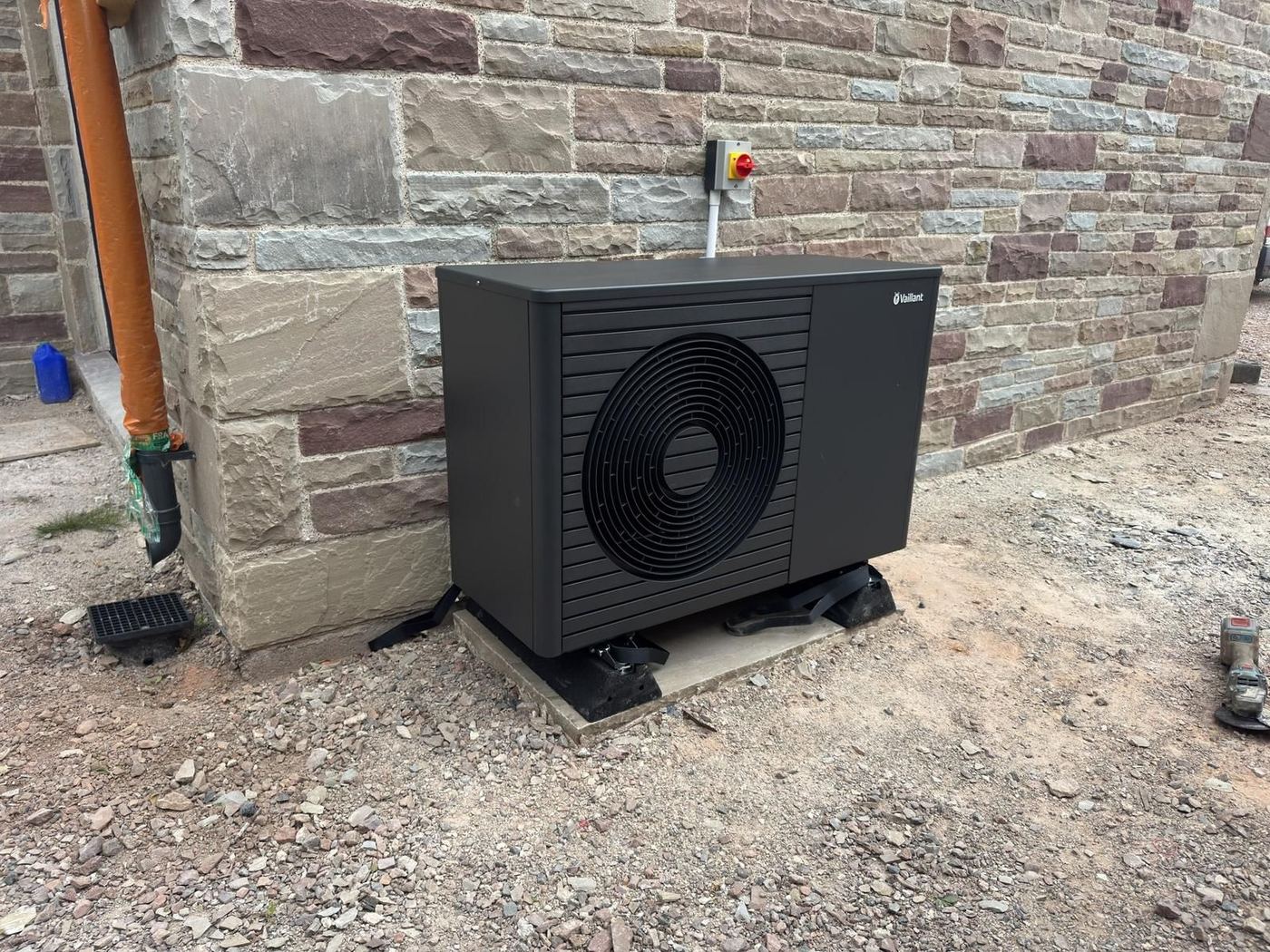 Anthracite Vaillant air source heat pump installed against a stone wall