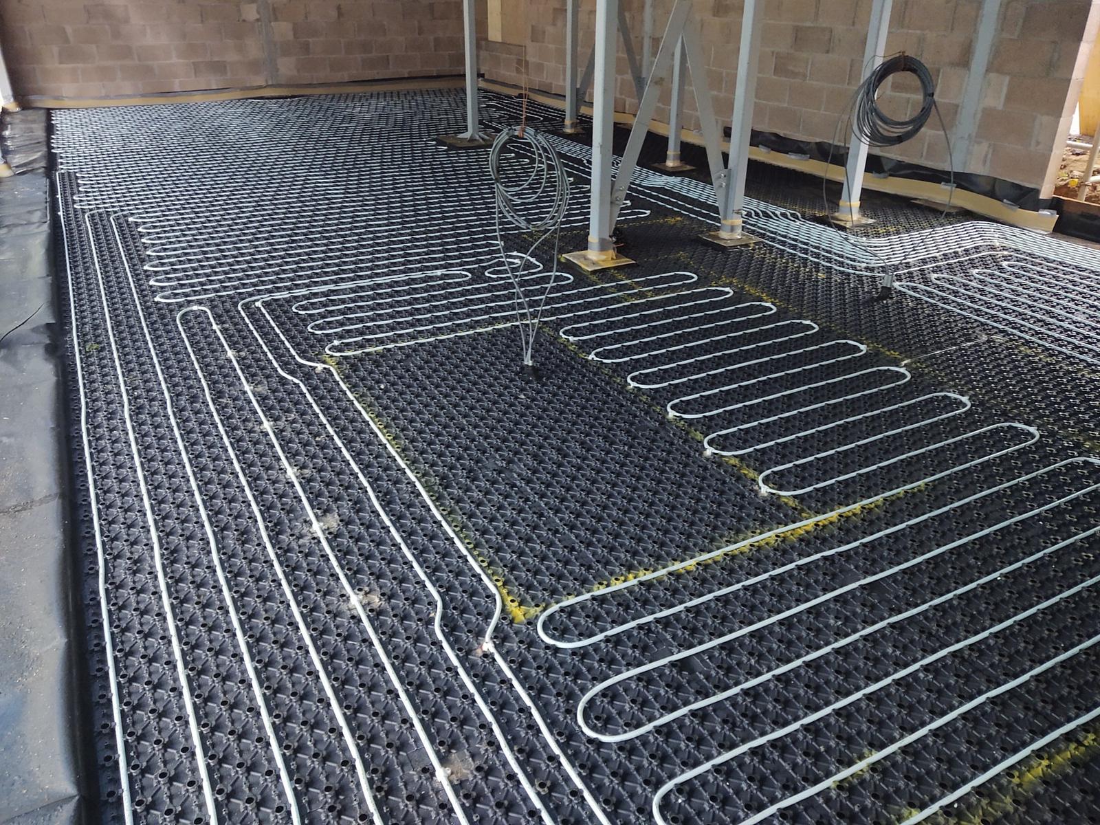 Underfloor heating pipe laid into black castellated panels before screeding