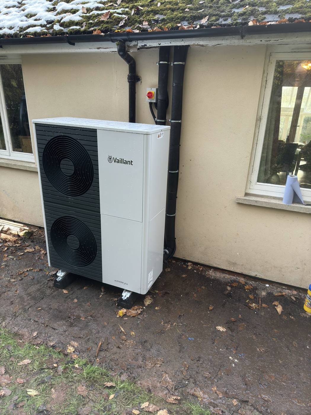 Vaillant air source heat pump installed against a rendered house wall