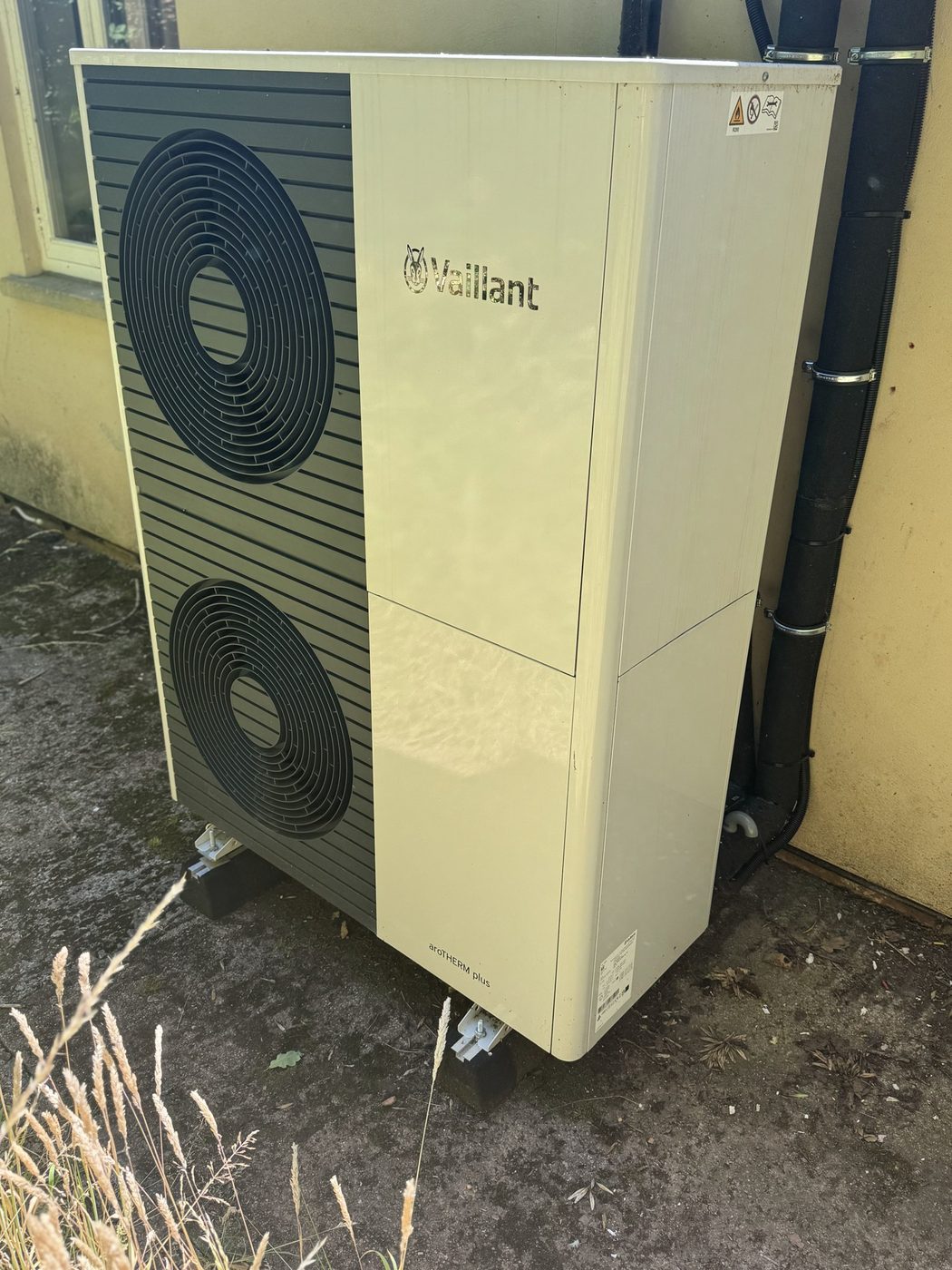 A Vaillant aroTHERM outdoor heat pump unit against a rendered wall