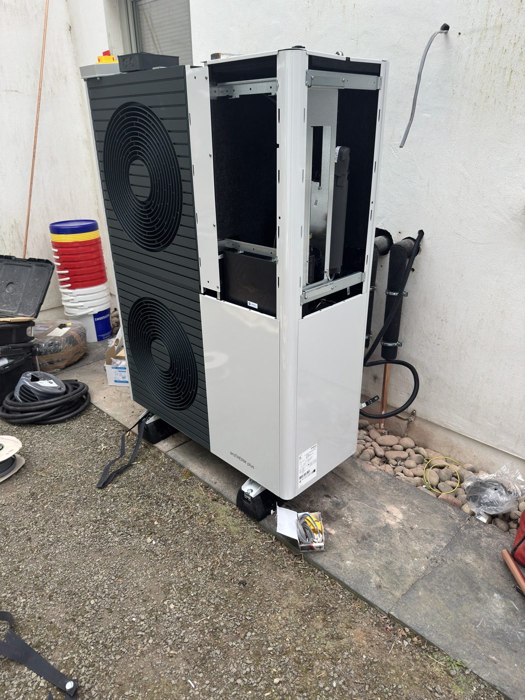 An outdoor heat pump unit with its casing removed, exposing the internal frame during a service