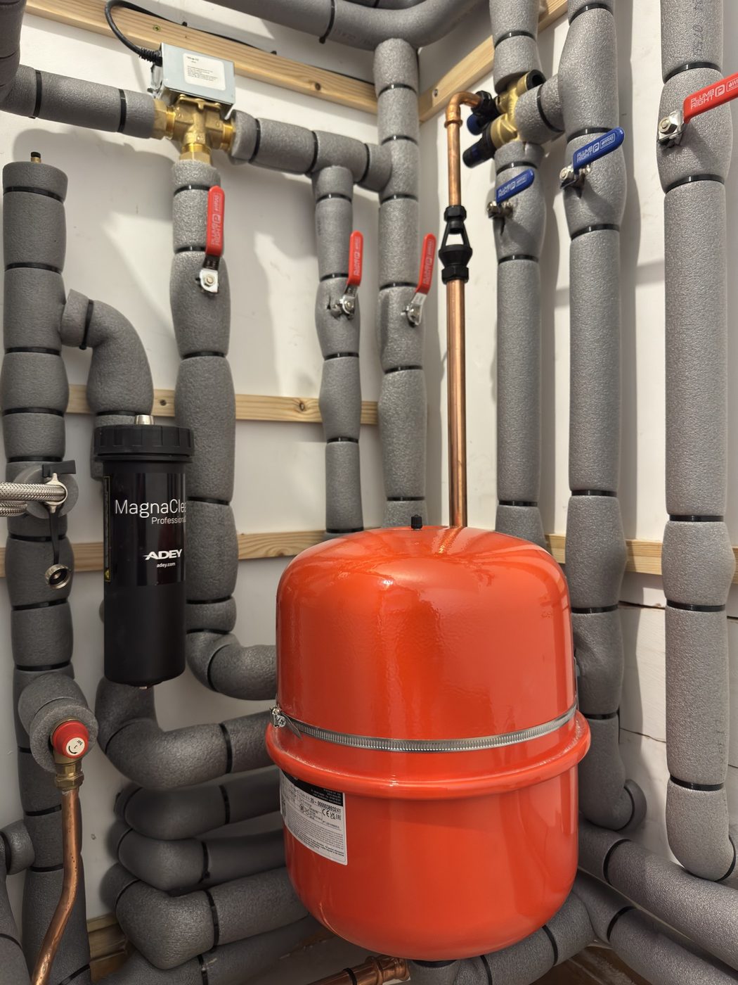 A magnetic filter, expansion vessel and lagged pipework on a tidy plant wall