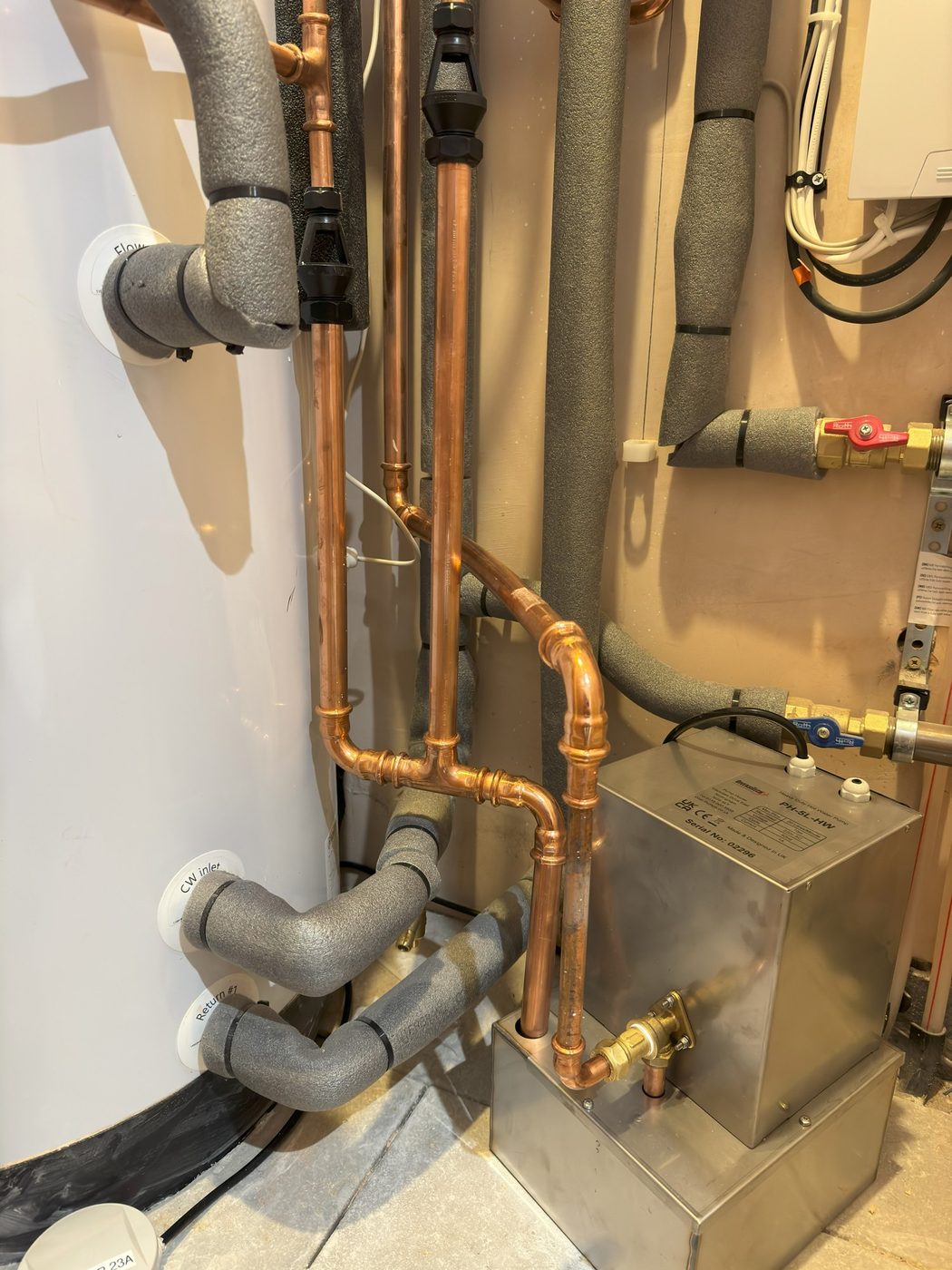 A hot water cylinder, buffer tank and copper pipework in a plant space