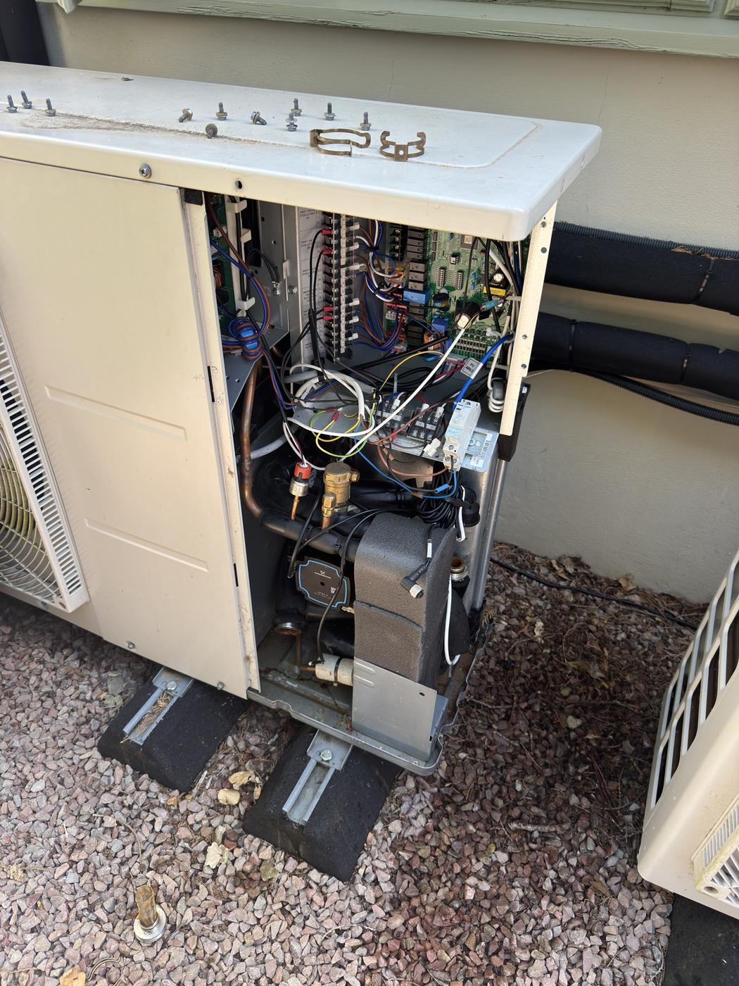 Heat pump with the front casing off during a visit, compressor and internal pipework visible