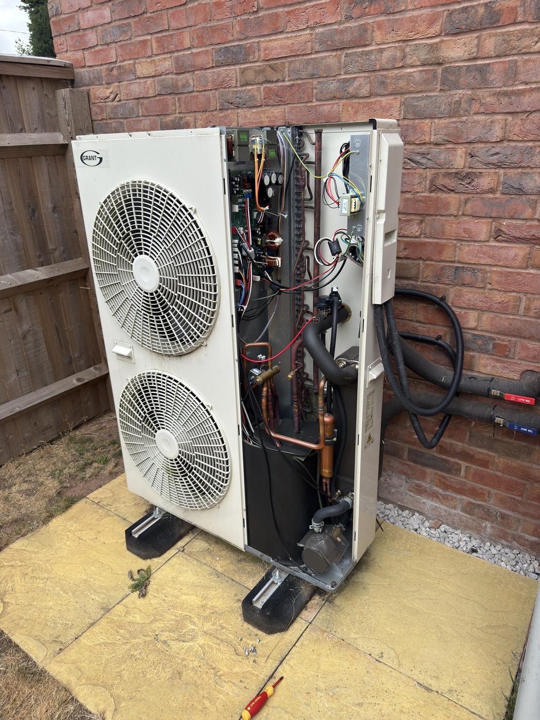 Heat pump outdoor unit with the side casing removed on site, internal pipework and boards exposed for fault finding