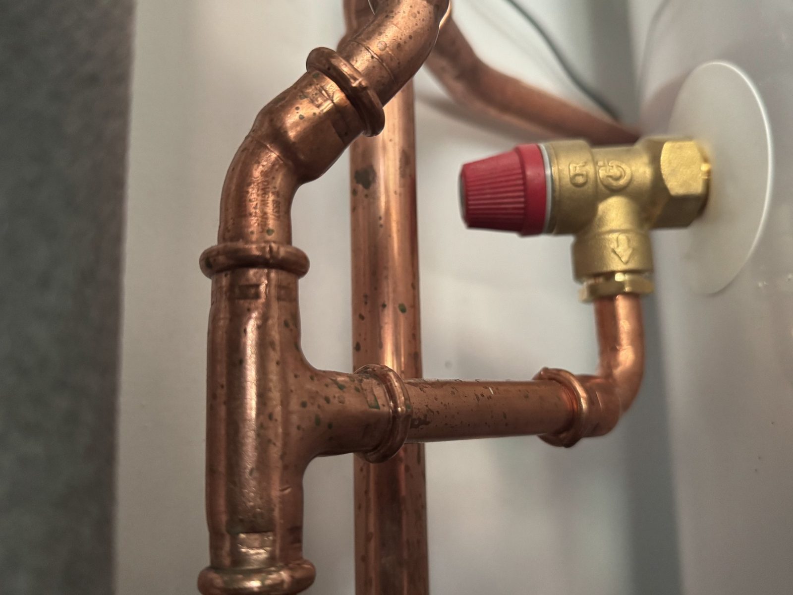 Pressure relief valve and copper pipework on a hot water cylinder, checked at every service
