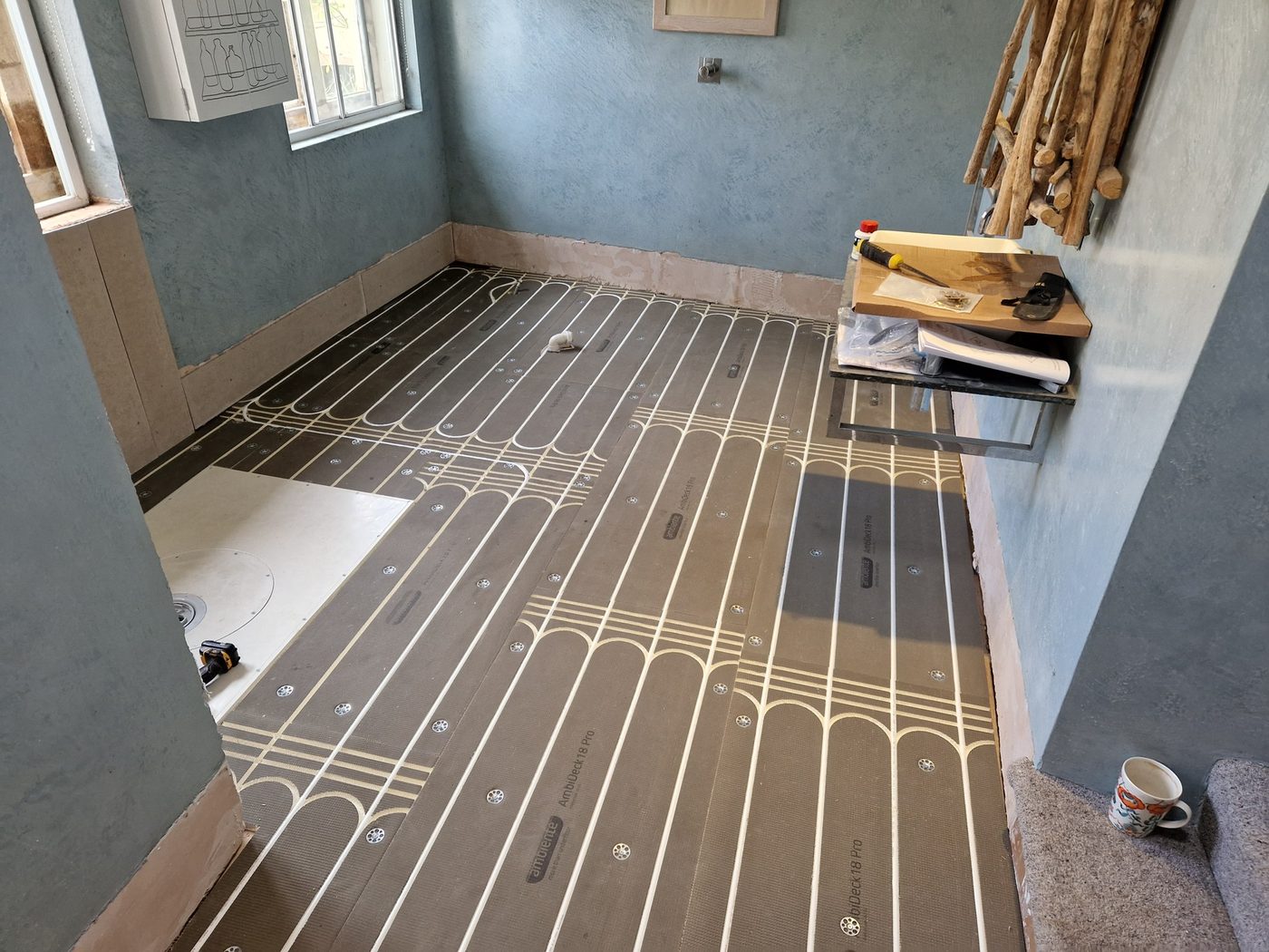 Low-profile overlay underfloor heating boards laid across a room during a system upgrade