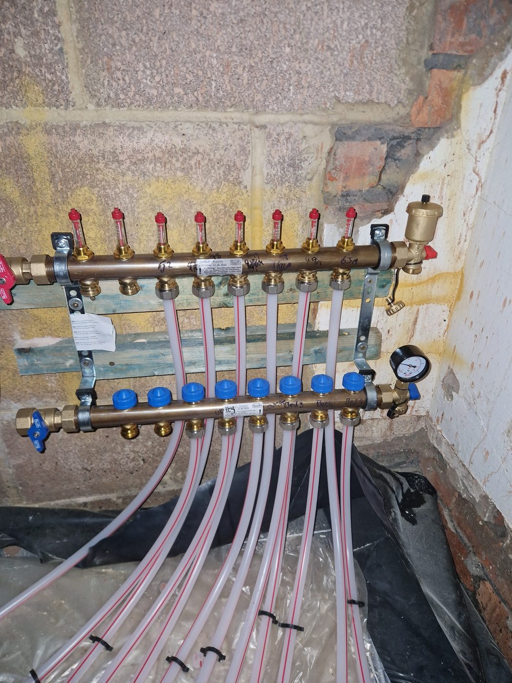 An underfloor heating manifold with flow meters and labelled circuits, checked on a service